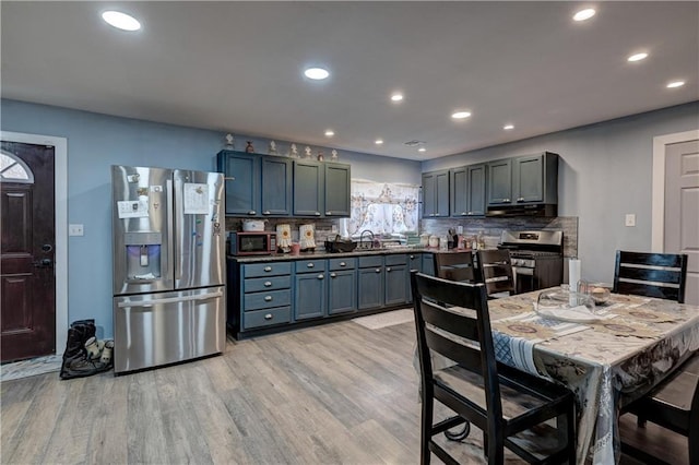 kitchen with decorative backsplash, stainless steel appliances, exhaust hood, sink, and light hardwood / wood-style flooring