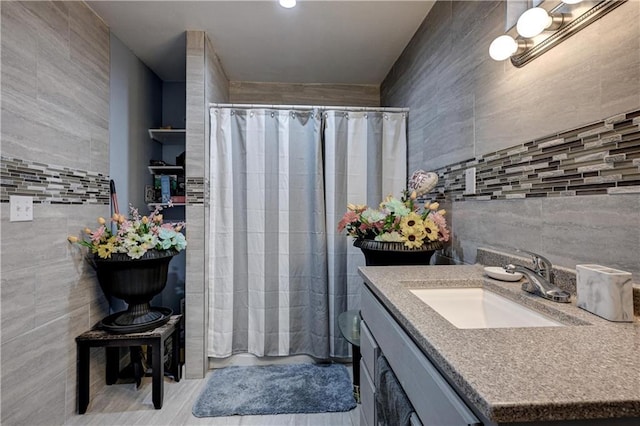 bathroom featuring a shower with shower curtain, vanity, and tile walls