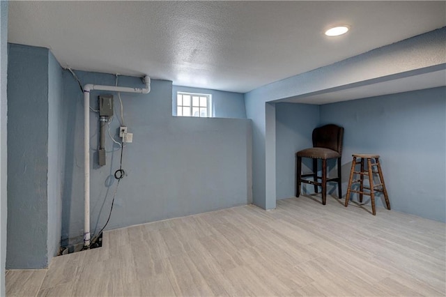 basement with a textured ceiling and light hardwood / wood-style flooring