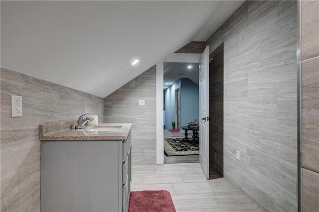 bathroom with vanity, tile walls, and lofted ceiling