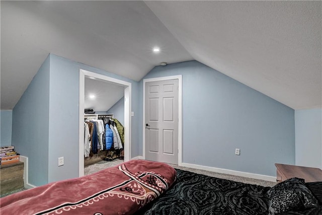 carpeted bedroom featuring a spacious closet, a closet, and lofted ceiling