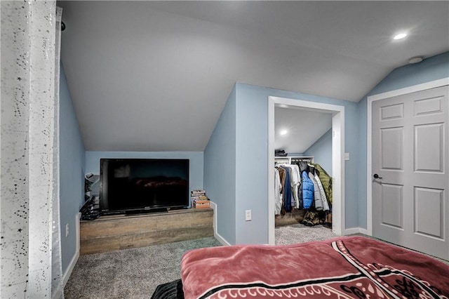 carpeted bedroom featuring a walk in closet, lofted ceiling, and a closet