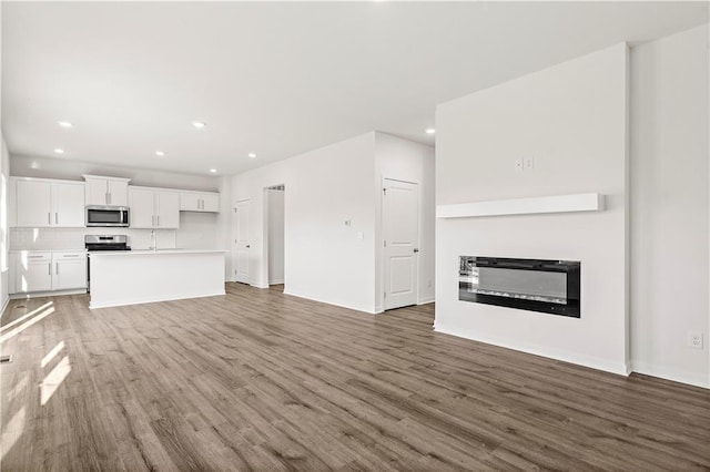 unfurnished living room with dark wood-type flooring and sink