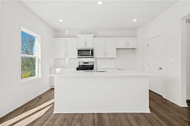 kitchen with white cabinetry, sink, stainless steel appliances, dark hardwood / wood-style flooring, and a kitchen island with sink