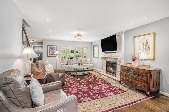 living area featuring wood finished floors, baseboards, a glass covered fireplace, and recessed lighting