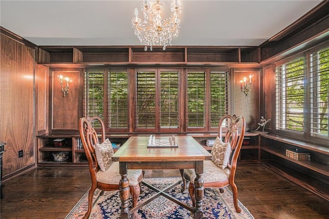 dining room featuring wooden walls, a chandelier, and wood finished floors