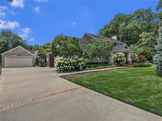 821 W 54th Ter, Kansas City, MO 64112 - view of front facade with a front lawn, stone siding, a chimney, and driveway