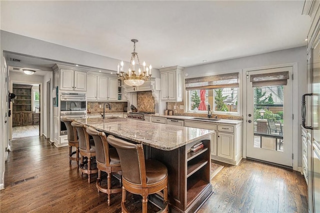 821 W 54th Ter, Kansas City, MO 64112 - kitchen featuring a chandelier, open shelves, dark wood-style floors, light stone counters, and appliances with stainless steel finishes