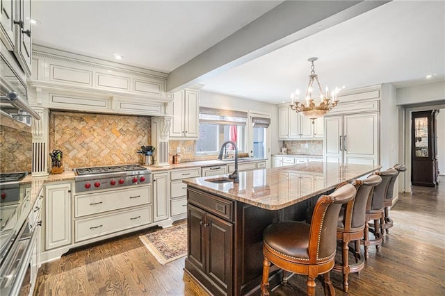 821 W 54th Ter, Kansas City, MO 64112 - kitchen featuring stainless steel gas cooktop, a chandelier, light stone countertops, dark wood-type flooring, and decorative backsplash