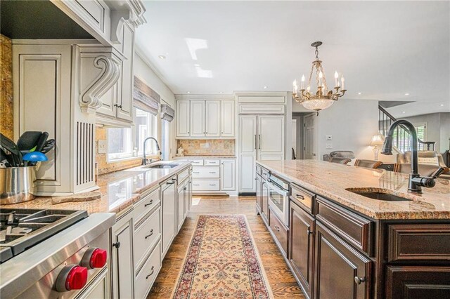 821 W 54th Ter, Kansas City, MO 64112 - kitchen featuring dark brown cabinetry, white cabinetry, a chandelier, tasteful backsplash, and a spacious island