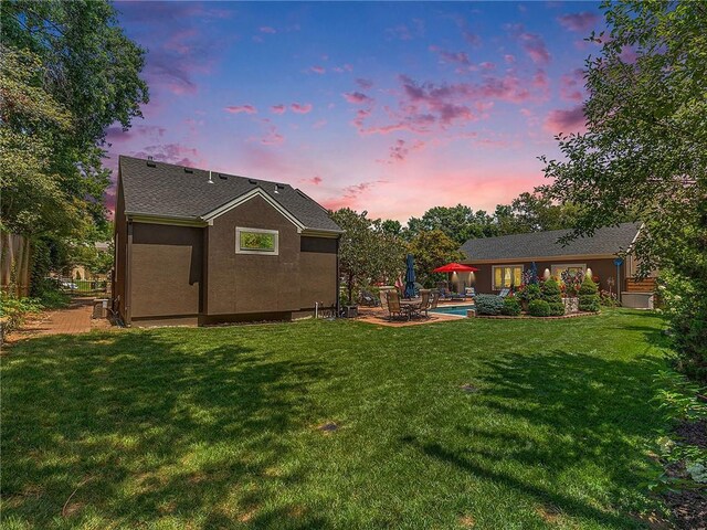 821 W 54th Ter, Kansas City, MO 64112 - back of property at dusk featuring a yard, a patio, stucco siding, and an outdoor pool