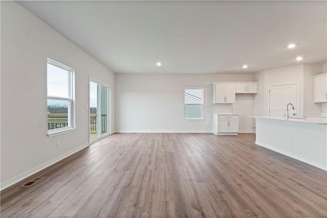 unfurnished living room with hardwood / wood-style flooring and sink