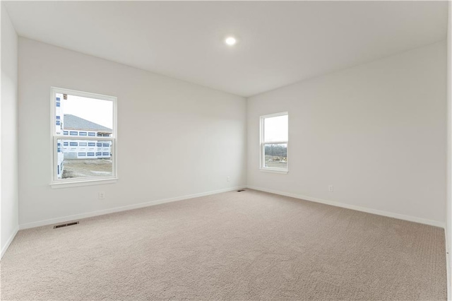 unfurnished room with light colored carpet and a wealth of natural light