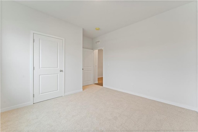 unfurnished bedroom with light colored carpet and a closet