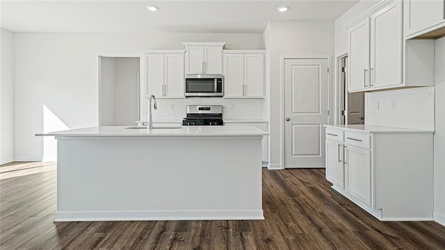 kitchen with white cabinetry, sink, dark hardwood / wood-style flooring, a kitchen island with sink, and appliances with stainless steel finishes