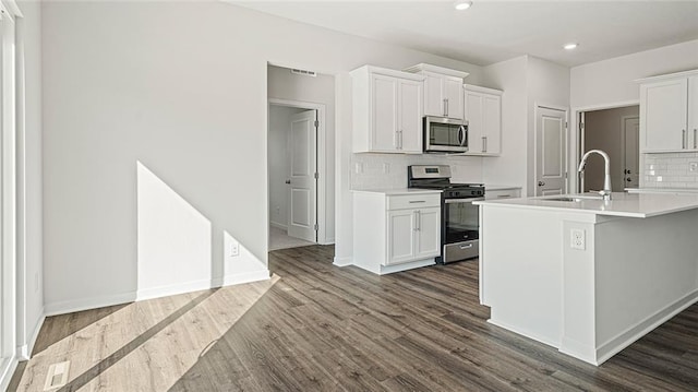 kitchen featuring sink, tasteful backsplash, a kitchen island with sink, white cabinets, and appliances with stainless steel finishes