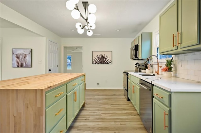 kitchen with green cabinets, stainless steel dishwasher, butcher block countertops, stove, and decorative light fixtures