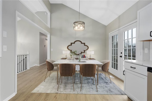 dining room with french doors, light wood-type flooring, high vaulted ceiling, and a notable chandelier