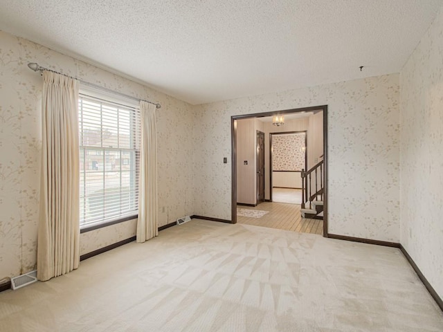 carpeted empty room with a textured ceiling