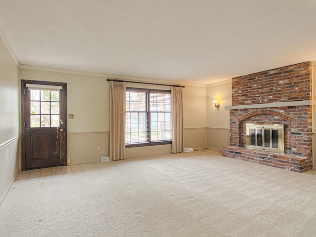 unfurnished living room featuring light carpet, a fireplace, a textured ceiling, and ornamental molding