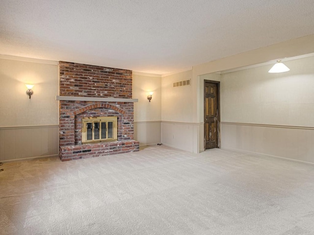 unfurnished living room featuring carpet flooring, a textured ceiling, and a brick fireplace