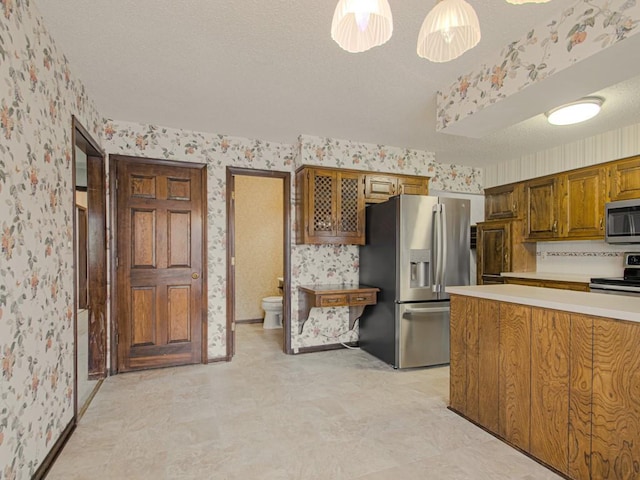 kitchen featuring decorative light fixtures, a textured ceiling, and stainless steel appliances