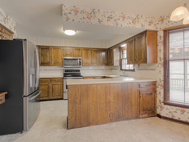 kitchen featuring a textured ceiling, sink, kitchen peninsula, and stainless steel appliances