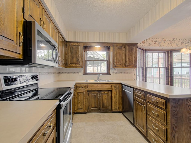 kitchen featuring kitchen peninsula, appliances with stainless steel finishes, tasteful backsplash, a textured ceiling, and sink