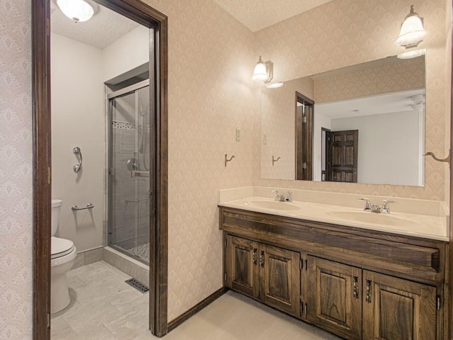 bathroom featuring vanity, a textured ceiling, toilet, and a shower with door