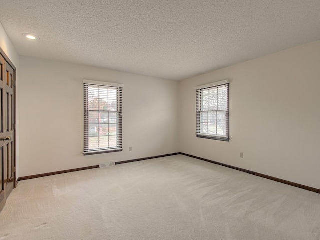 empty room featuring a textured ceiling and light carpet