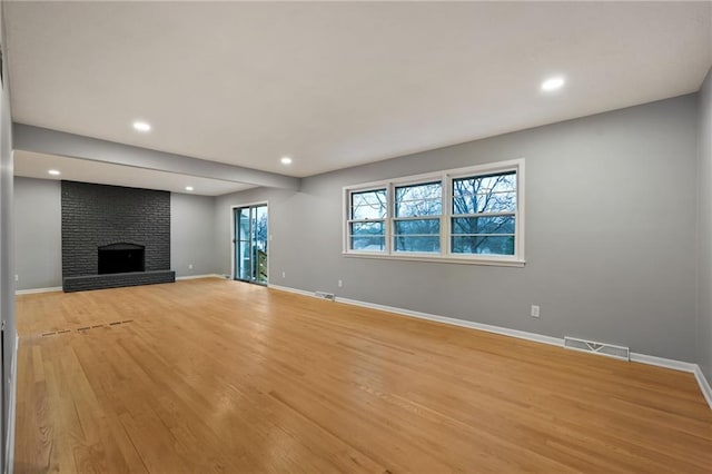 unfurnished living room featuring a fireplace and light hardwood / wood-style flooring