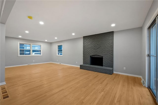 unfurnished living room with a fireplace and light wood-type flooring