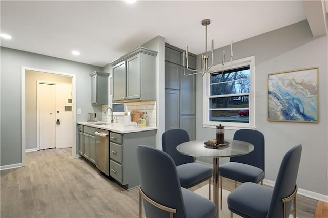 kitchen with gray cabinetry, decorative light fixtures, stainless steel dishwasher, and tasteful backsplash