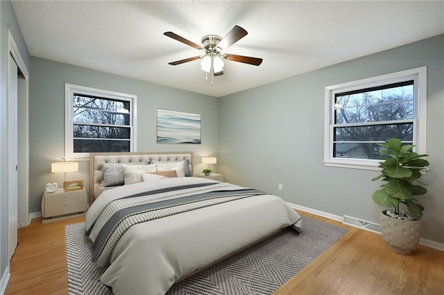 bedroom with multiple windows, light wood-type flooring, and ceiling fan