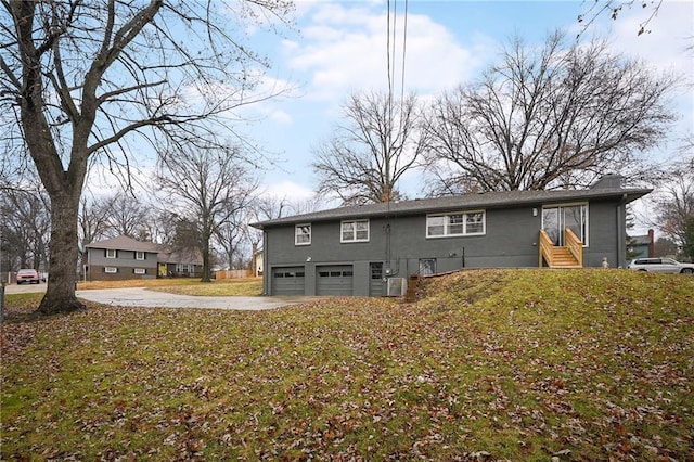 back of property featuring a lawn, a garage, and central AC