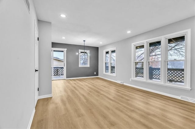 unfurnished room with a notable chandelier and light hardwood / wood-style flooring