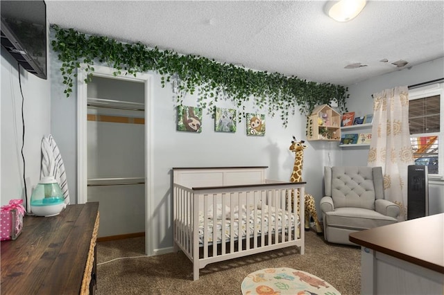 bedroom featuring a crib, a textured ceiling, a closet, and dark colored carpet