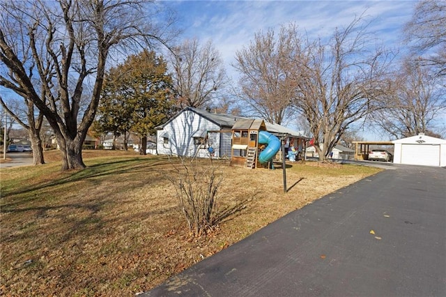 view of yard featuring a garage, a playground, and an outbuilding