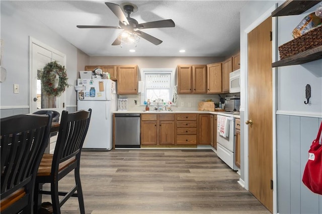 kitchen with ceiling fan, sink, white appliances, decorative backsplash, and light wood-type flooring