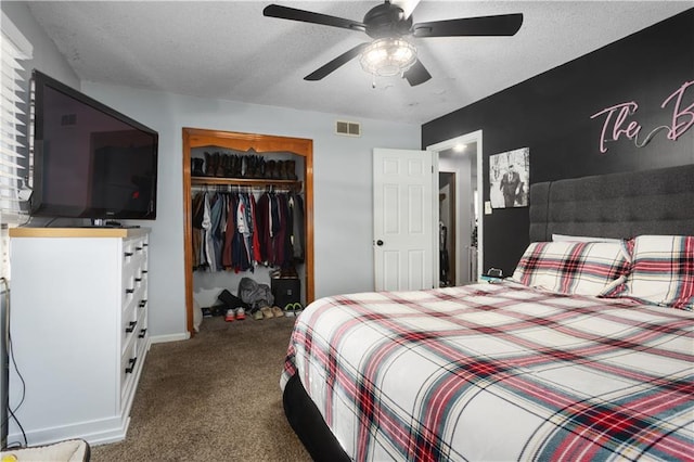 bedroom with a textured ceiling, dark carpet, a closet, and ceiling fan