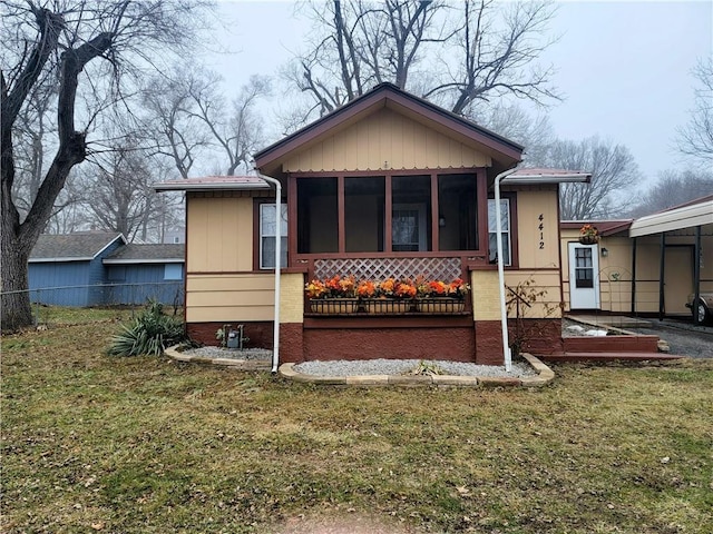 rear view of house featuring a yard and a sunroom