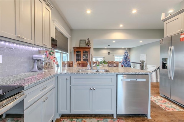 kitchen with kitchen peninsula, tasteful backsplash, stainless steel appliances, ceiling fan, and sink