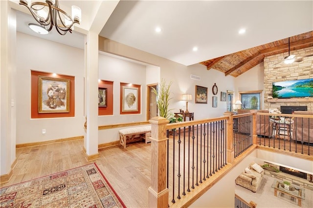 hall with wooden ceiling, high vaulted ceiling, light wood-type flooring, beam ceiling, and a chandelier