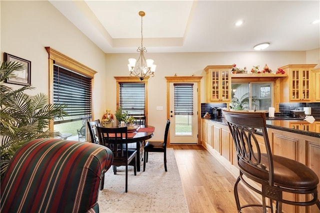 dining room featuring a notable chandelier, light hardwood / wood-style floors, and a tray ceiling