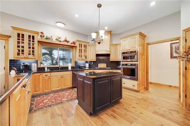 kitchen with pendant lighting, decorative backsplash, stainless steel appliances, and light hardwood / wood-style flooring