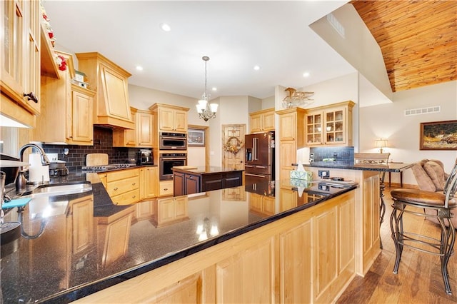 kitchen with sink, stainless steel appliances, backsplash, decorative light fixtures, and a kitchen island