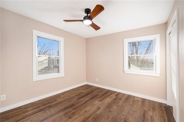 spare room with a ceiling fan, dark wood-style floors, and baseboards