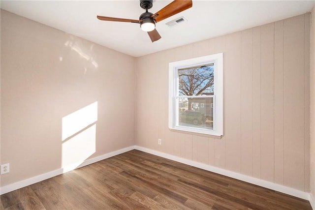 unfurnished room with visible vents, baseboards, ceiling fan, and dark wood-style flooring