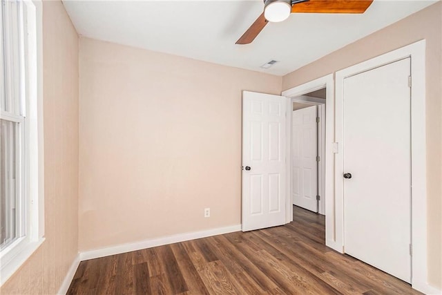 unfurnished bedroom with a ceiling fan, visible vents, wood finished floors, and baseboards