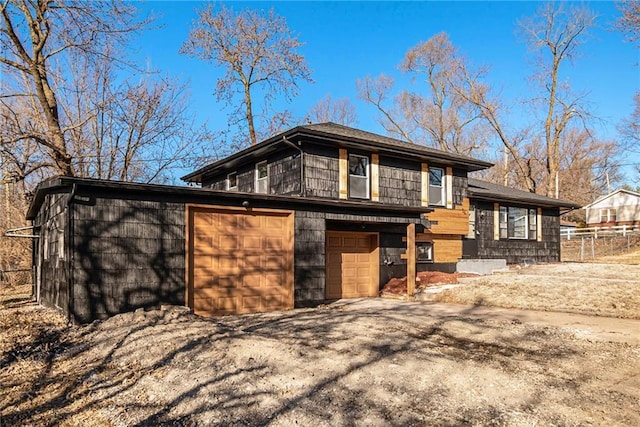 view of front of home with aphalt driveway, an attached garage, and fence